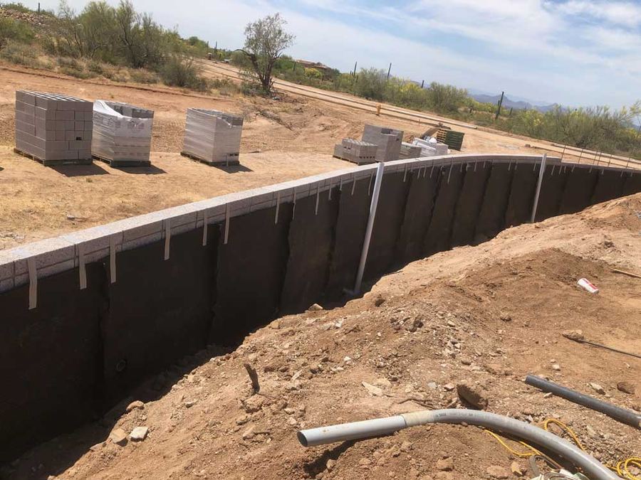 Below-grade waterproofing membrane on a block wall before backfill