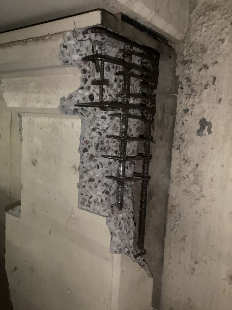 Concrete column with spalled concrete and exposed rebar, before repair
