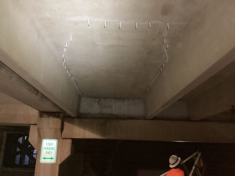Epoxy injection ports along cracks in a parking garage beam